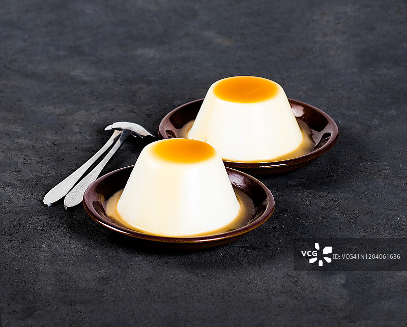 意大利甜点意式奶冻，奶油果冻和焦糖酱在深色背景上图片素材