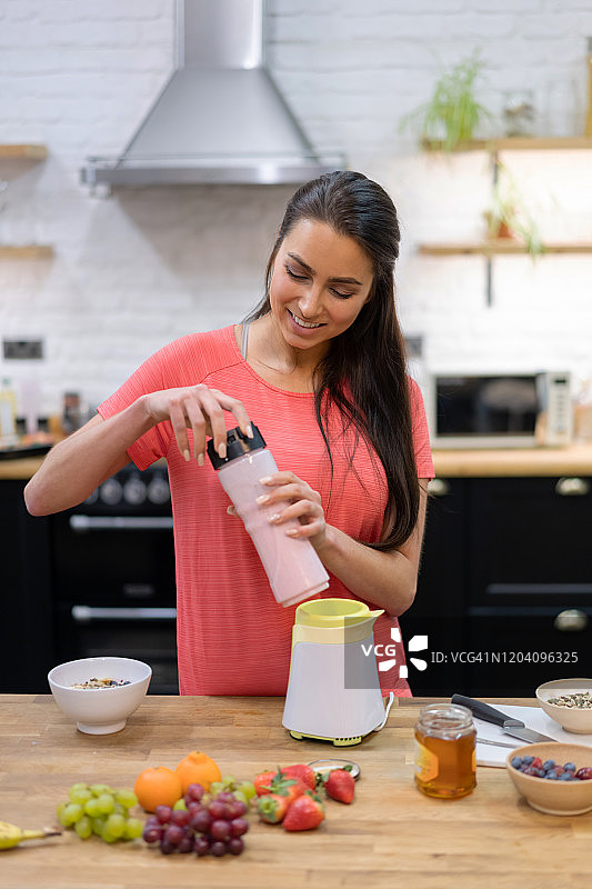 快乐的女人在家制作冰沙图片素材