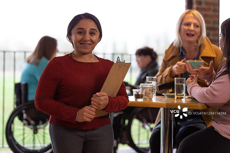 笑容满面的女服务员站在咖啡馆里图片素材