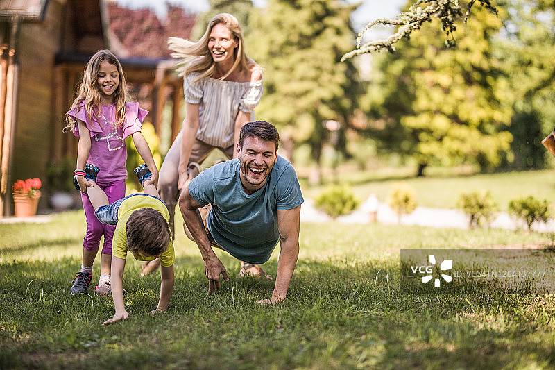 在后院玩独轮车比赛的快乐家庭图片素材