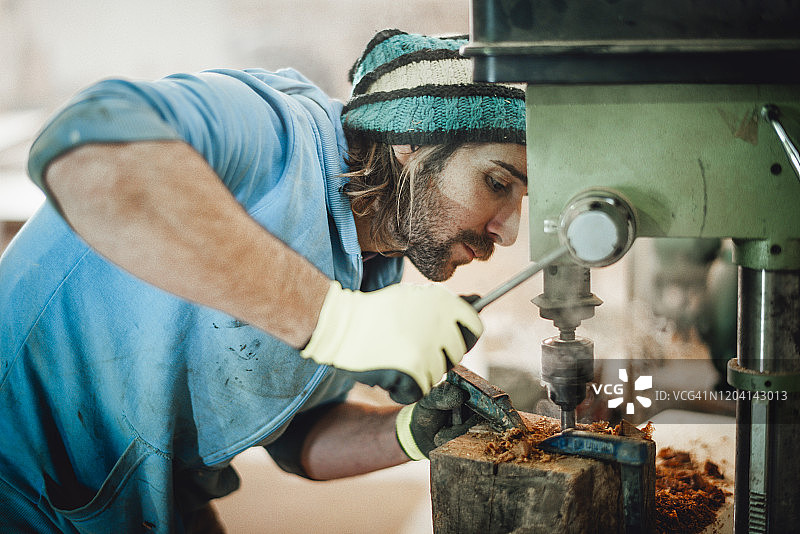 木匠在车间使用钻床在木头上钻孔图片素材