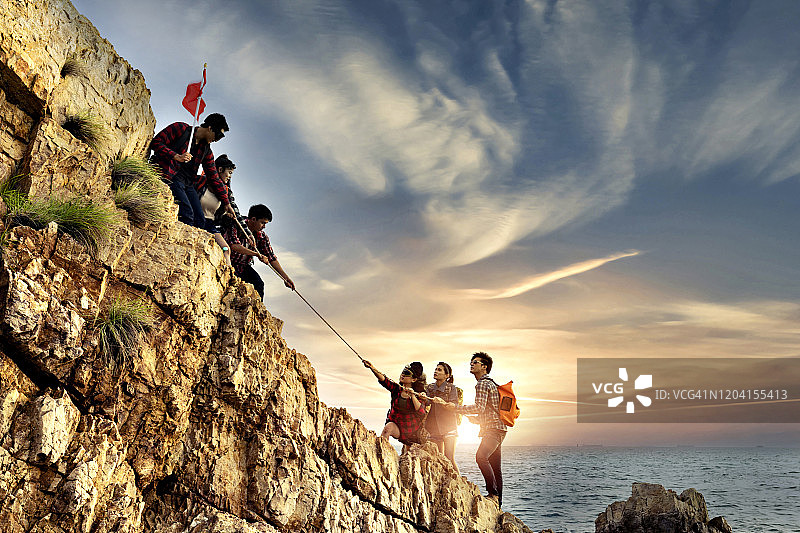 男人和女人徒步旅行者攀登悬崖。互助和团队合作概念图片素材