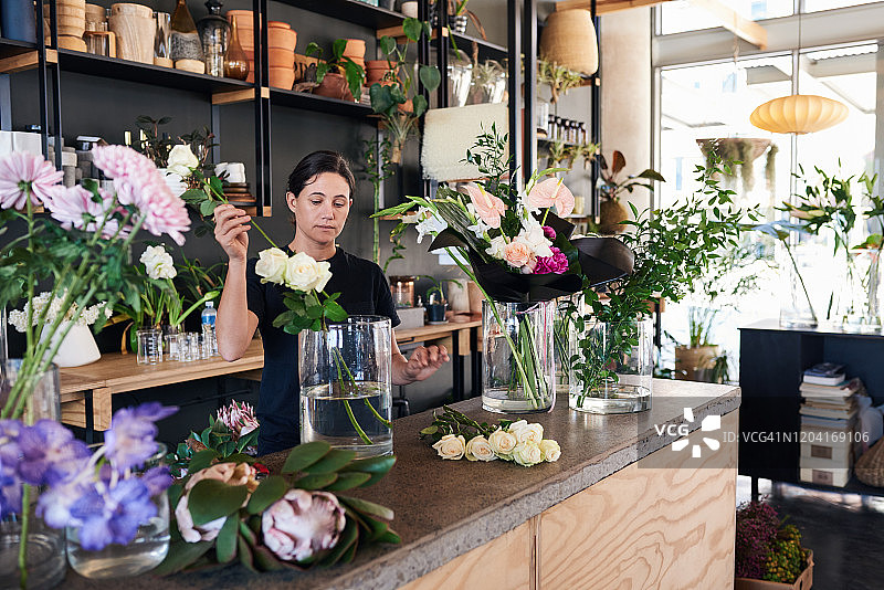 花店店员将玫瑰放入玻璃花瓶中图片素材