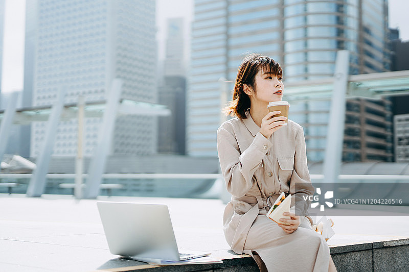 都市阳台上吃午餐的亚洲年轻女商人图片素材