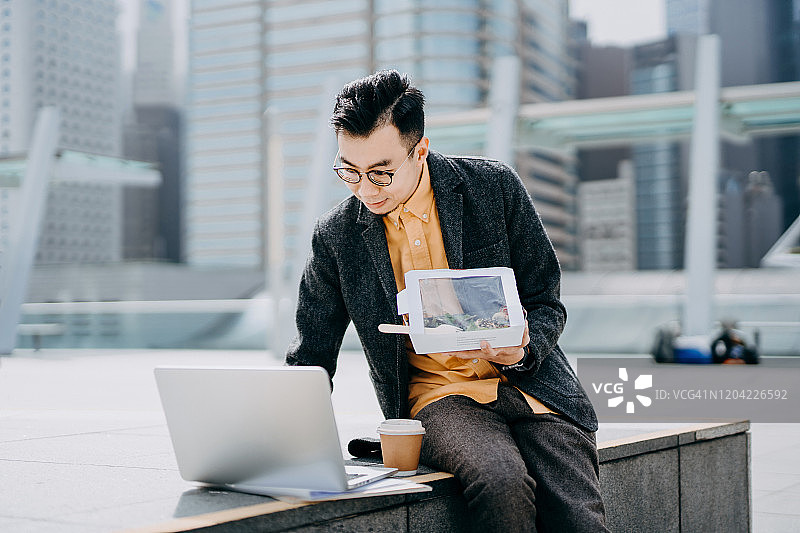年轻的亚洲男商人在城市阳台上用笔记本电脑工作图片素材