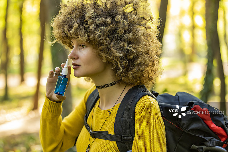 年轻女人在户外使用鼻腔喷雾缓解过敏图片素材
