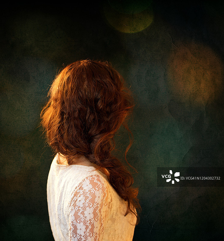 长发红发女子背影，身穿白色蕾丝复古上衣，深绿色纹理背景与金色散景图片素材