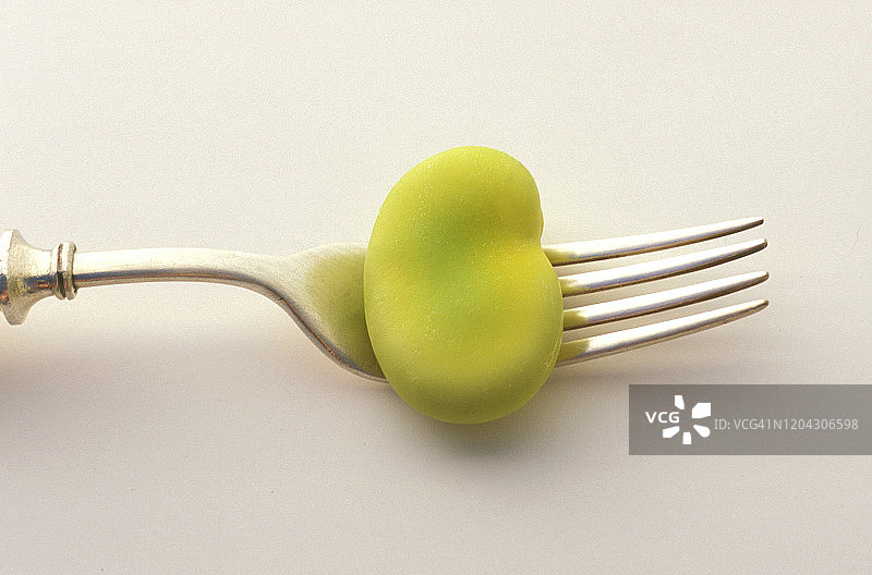 白色背景上的古董叉子上的蚕豆特写图片素材