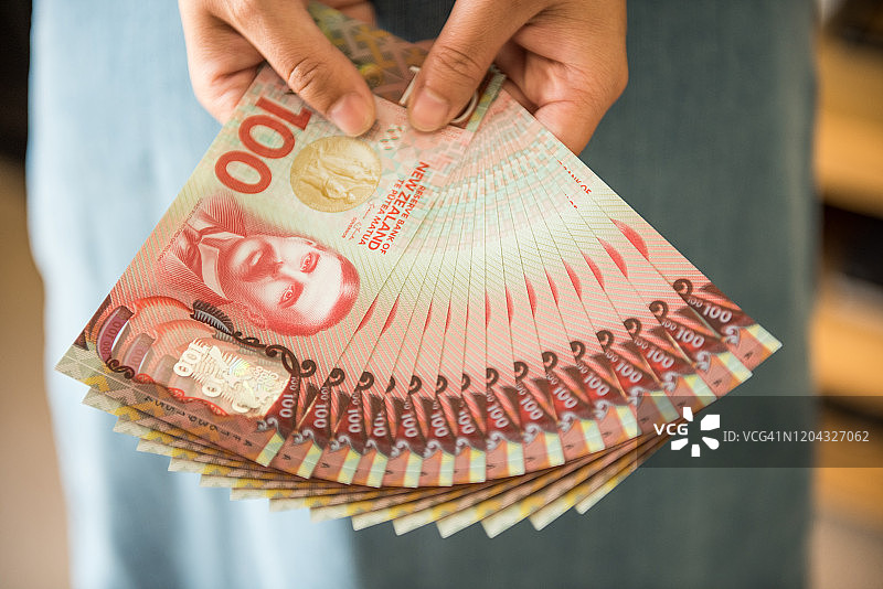 手持展开的新西兰货币的女人图片素材