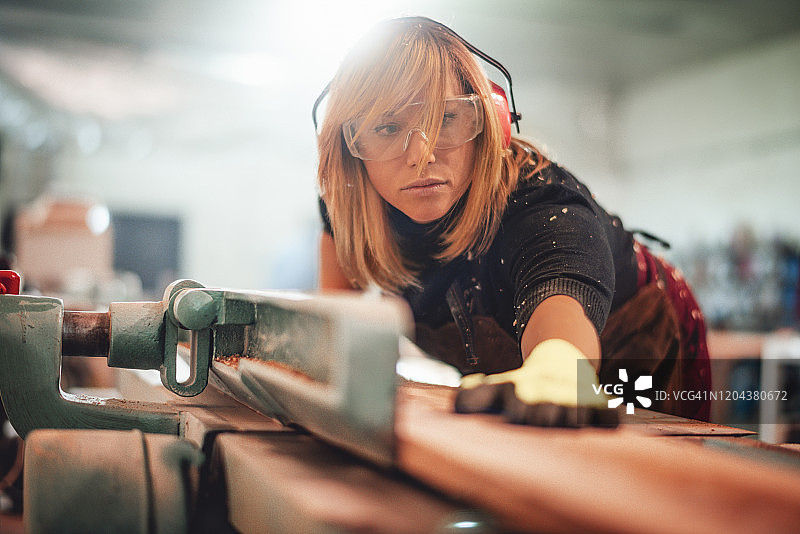工匠使用锯子在工作台上切割木板图片素材