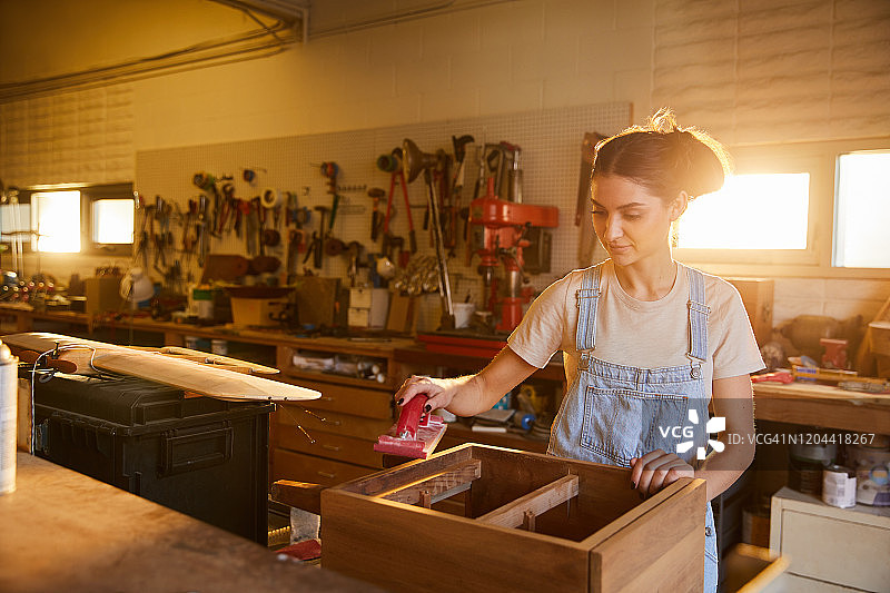 在木工店打磨橱柜的年轻女人图片素材