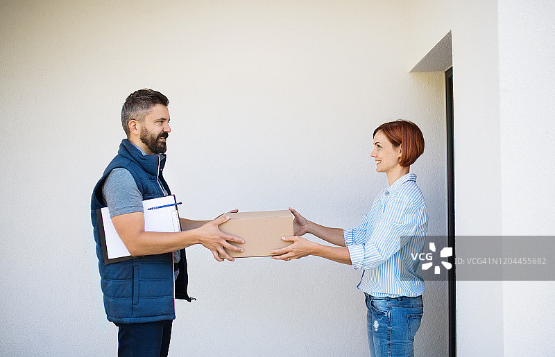 快递员给年轻女子送包裹图片素材