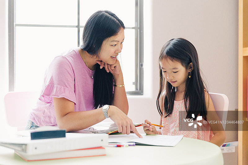 母亲正在帮助女儿做功课图片素材