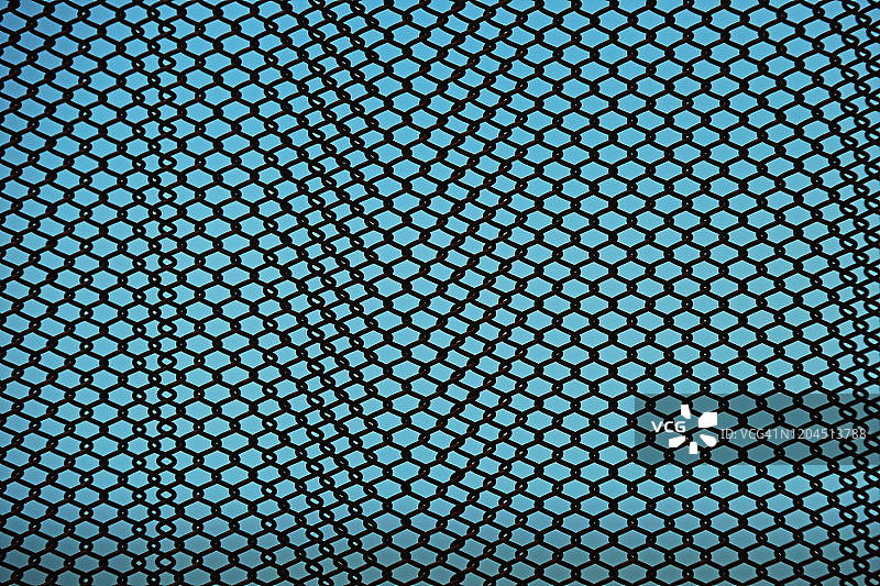 蓝色背景下悬挂的链式金属帘特写图片素材