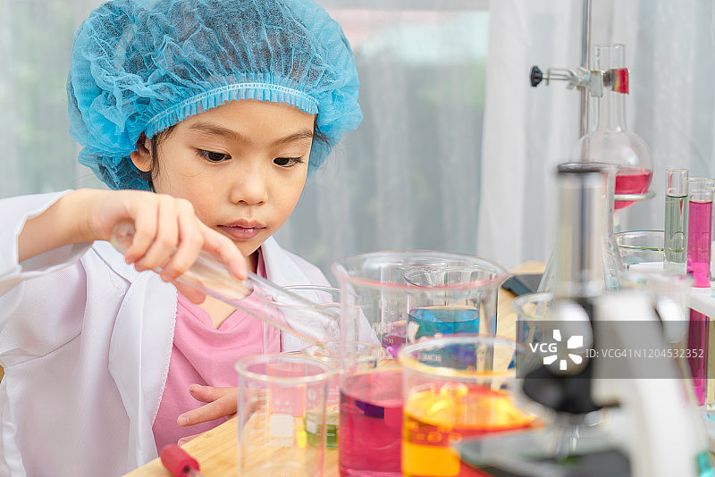 亚洲小女孩在配备彩色玻璃管的实验室里扮演科学家图片素材