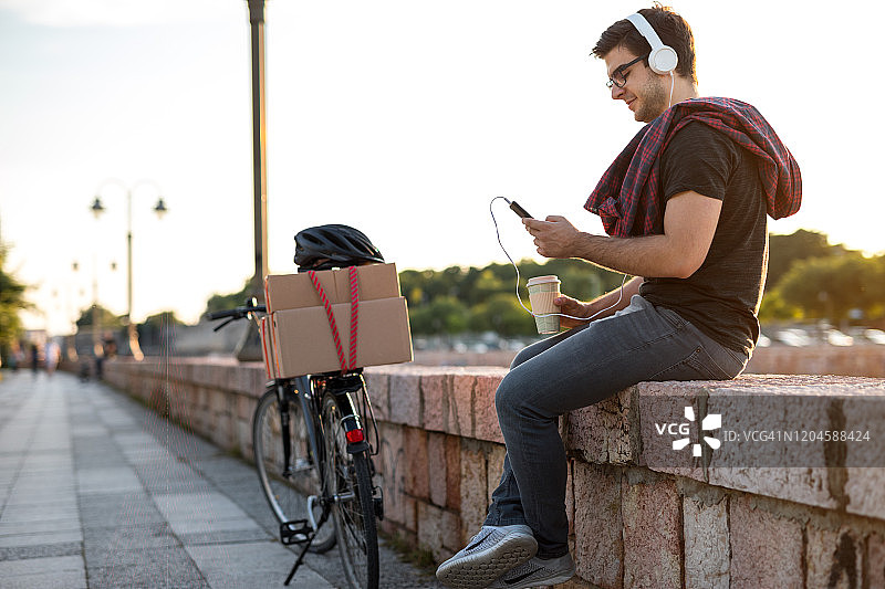 年轻的骑自行车者在河边听音乐图片素材