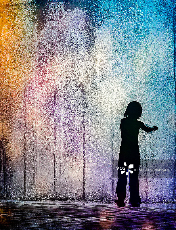美国，站在彩色喷泉中的儿童剪影图片素材