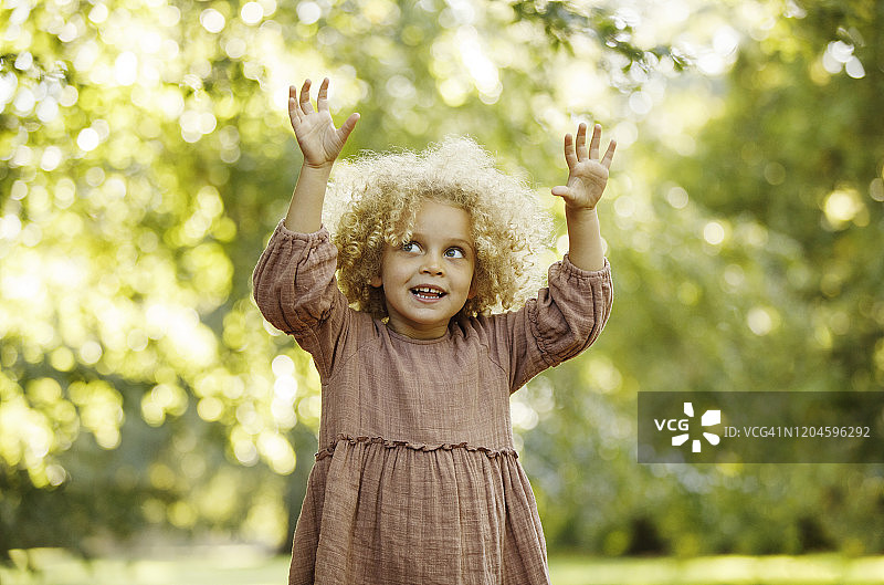 在公园里举起双手的快乐年轻女孩图片素材