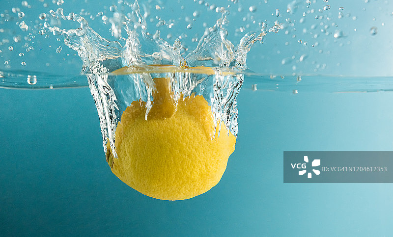 蓝色背景中柠檬溅入水中图片素材