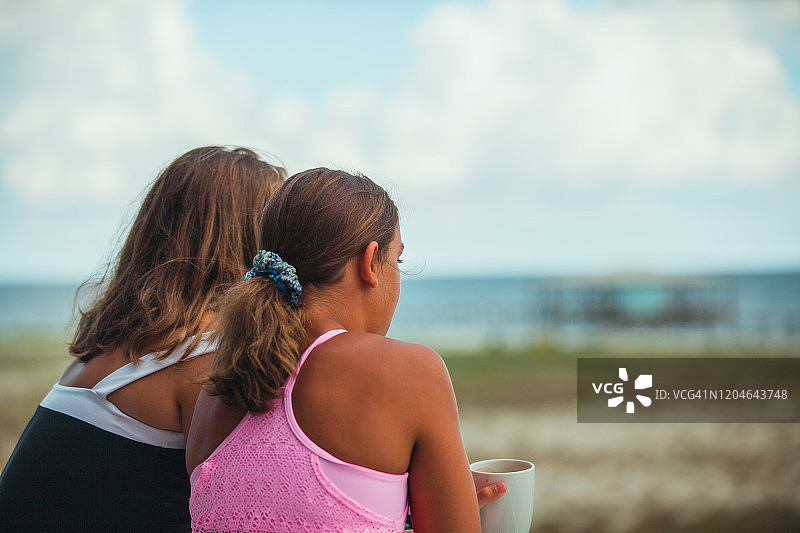 两个女孩在户外欣赏早晨的海滩景色图片素材