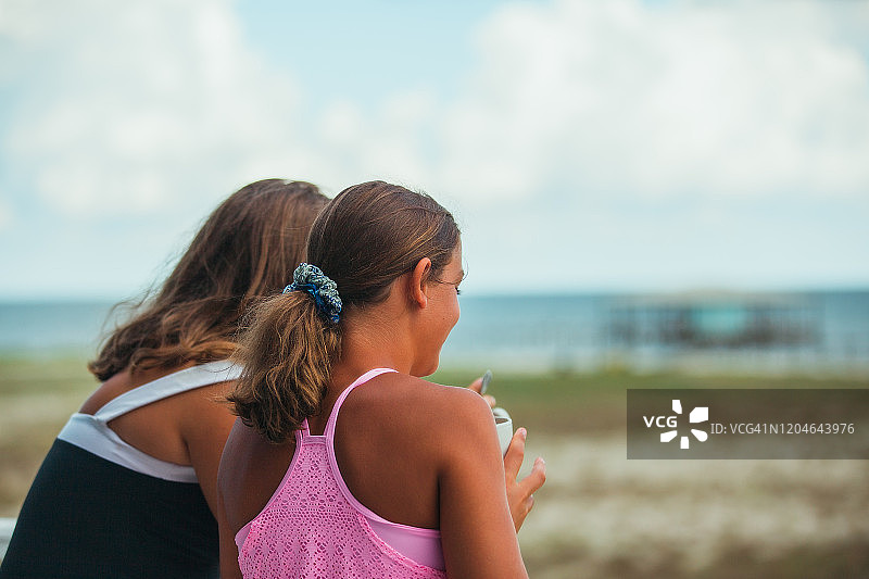 两个女孩在户外欣赏早晨的海滩景色图片素材