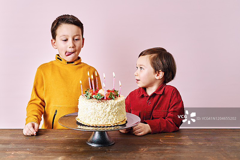 粉色背景上拿着生日蛋糕的可爱孩子们：生日派对大庆祝图片素材