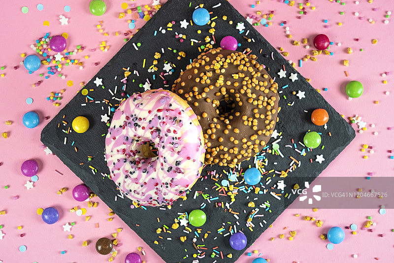 粉色背景上带有五彩纸屑的甜甜圈图片素材