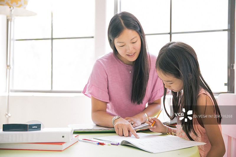 母亲正在帮助女儿做功课图片素材