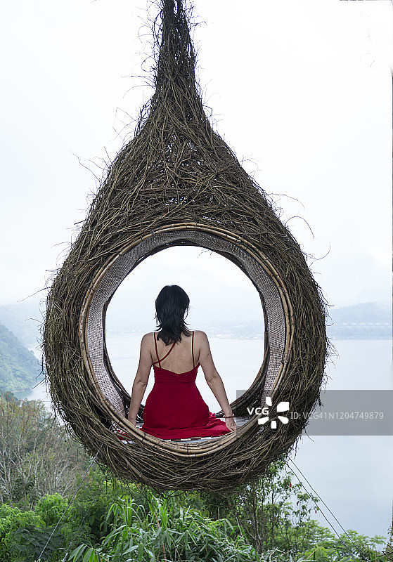 在人造木巢中，穿着红色连衣裙的亚洲女人图片素材