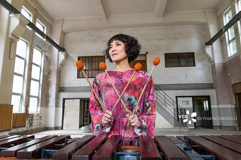 在废墟中演奏马林巴琴的亚洲年轻女子图片素材