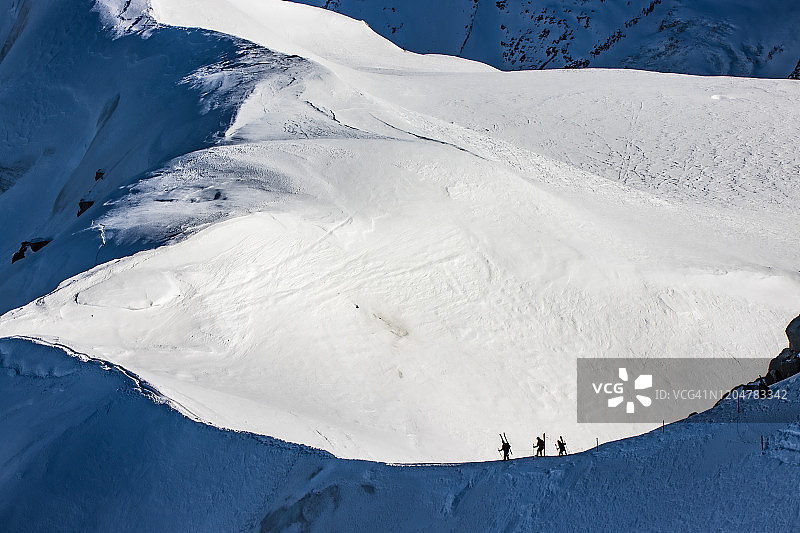 逆光滑雪者走向法国阿尔卑斯山图片素材