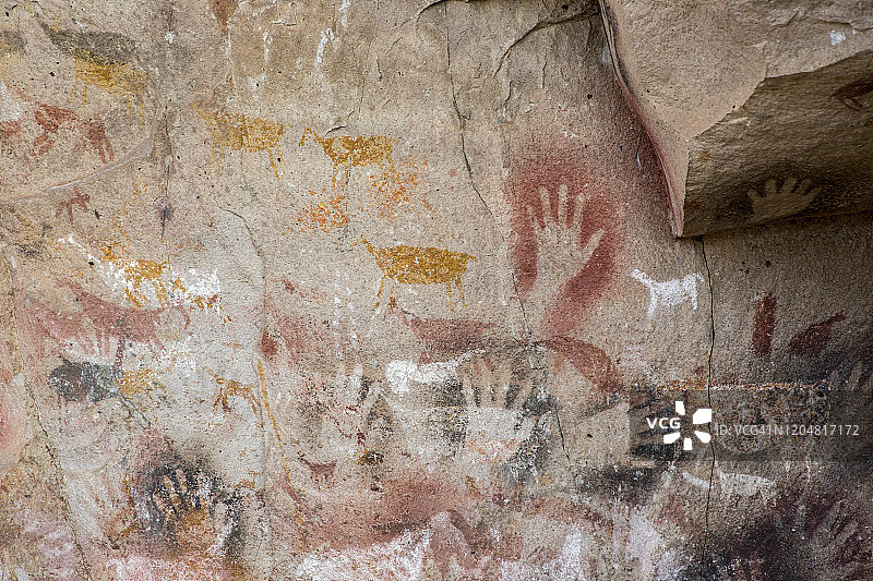 悬崖墙壁上手和动物的史前绘画特写图片素材