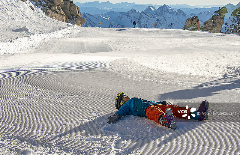 快乐的小滑雪者躺在滑雪道上，奥地利 Hintertux Glacier 滑雪胜地图片素材