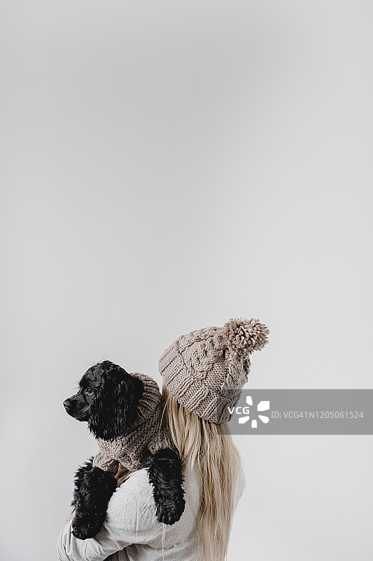 金发女人抱着穿着相配针织衫的狗图片素材