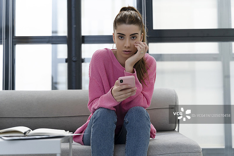 坐在沙发上使用智能手机的年轻女子肖像图片素材
