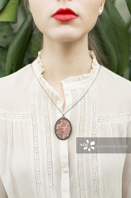 穿着蕾丝衬衫佩戴吊坠的年轻女子（局部）图片素材