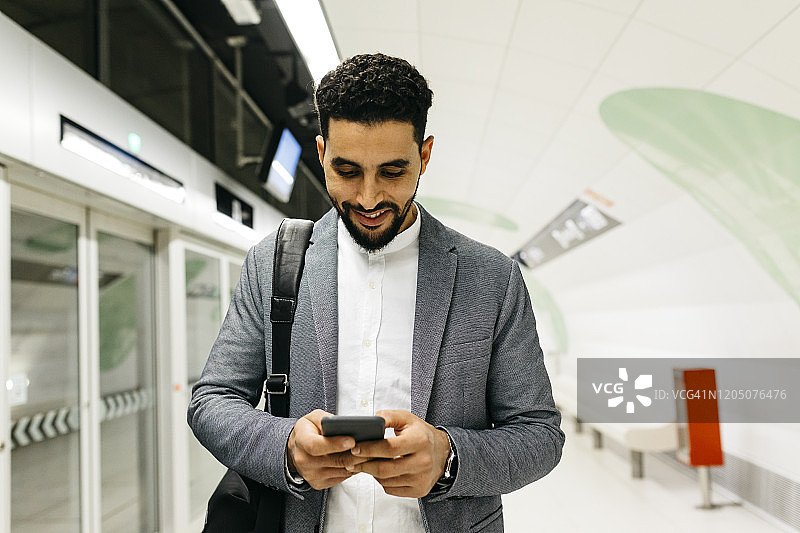 在地铁站使用手机的年轻商人图片素材