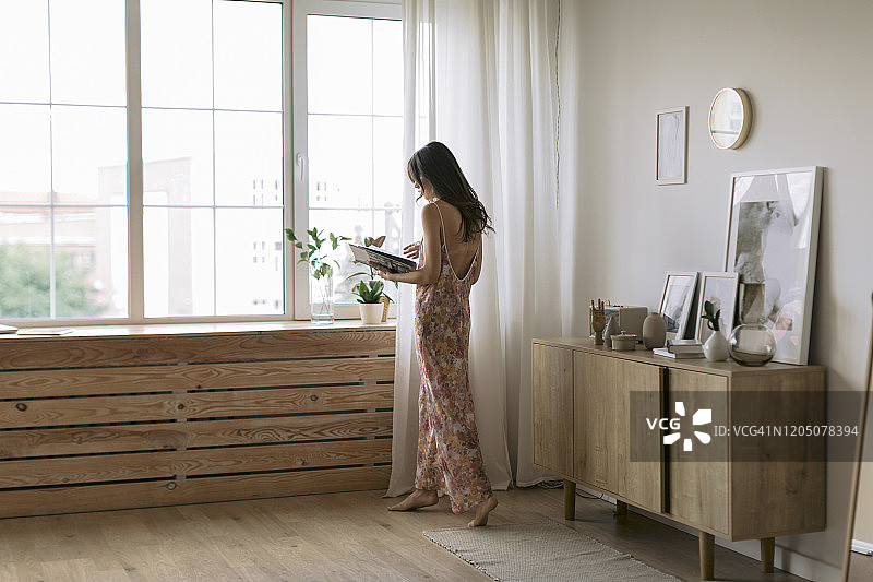 在家中窗边读书的年轻女人图片素材