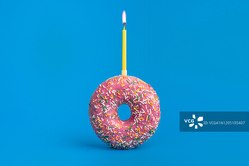 蓝色背景上洒满粉色节日甜甜圈和蜡烛图片素材