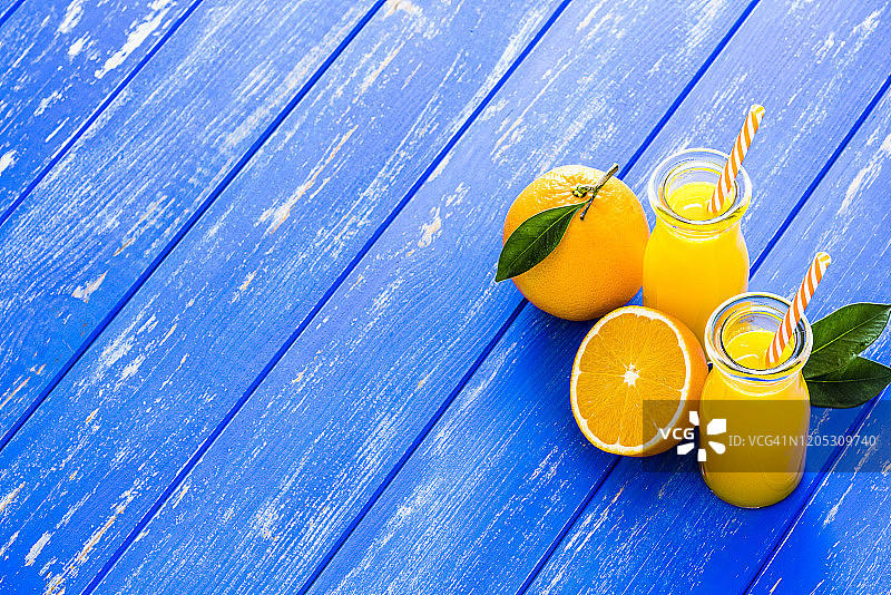 蓝色桌子上带空白区域的两瓶橙汁图片素材