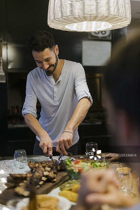 快乐的年轻人为朋友切烤肉，一起用餐图片素材