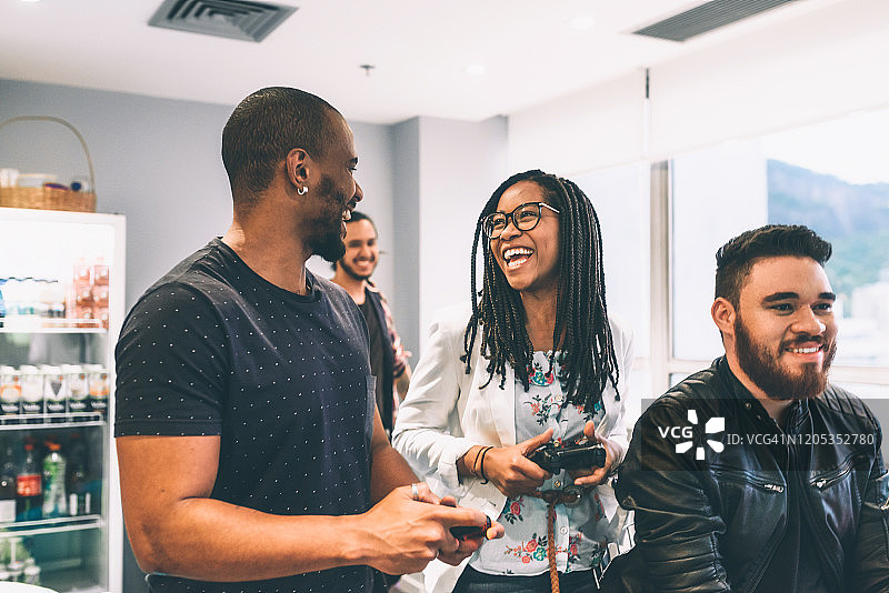 办公室里玩电子游戏的三个快乐的年轻巴西人图片素材