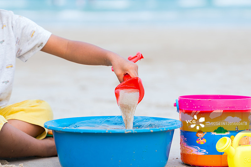 快乐的小女孩在海边度假玩沙子，堆沙堡图片素材