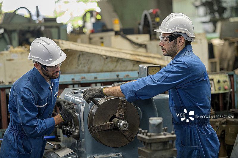两名产业工人在金属加工行业操作数控车床，团队合作概念图片素材