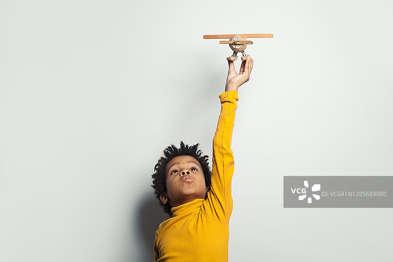 在白色背景上玩飞机模型的黑人儿童男孩图片素材