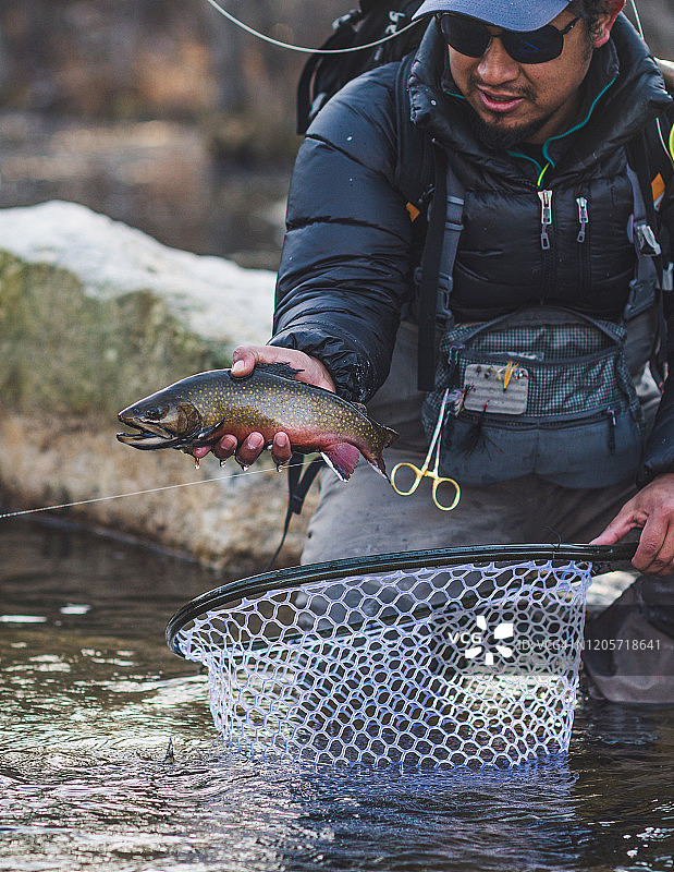 一名男子在寒冷的缅因州早晨捕获一条溪鳟鱼图片素材