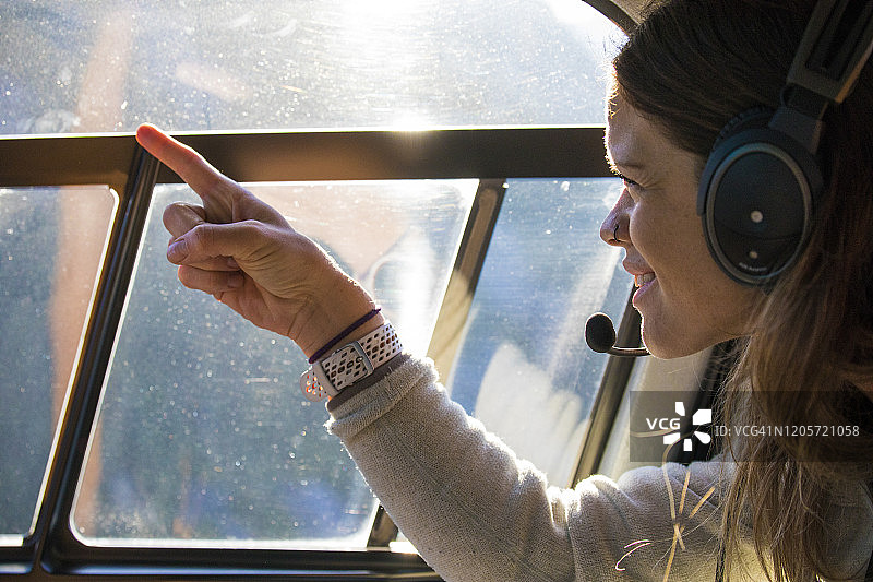 在直升机内指向窗外景色的年轻人图片素材