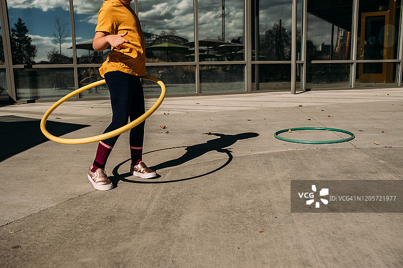 年轻女孩在阳光明媚的露台上尝试呼啦圈图片素材