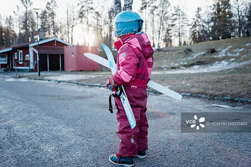 年轻女孩拿着越野滑雪板走向瑞典的斜坡图片素材