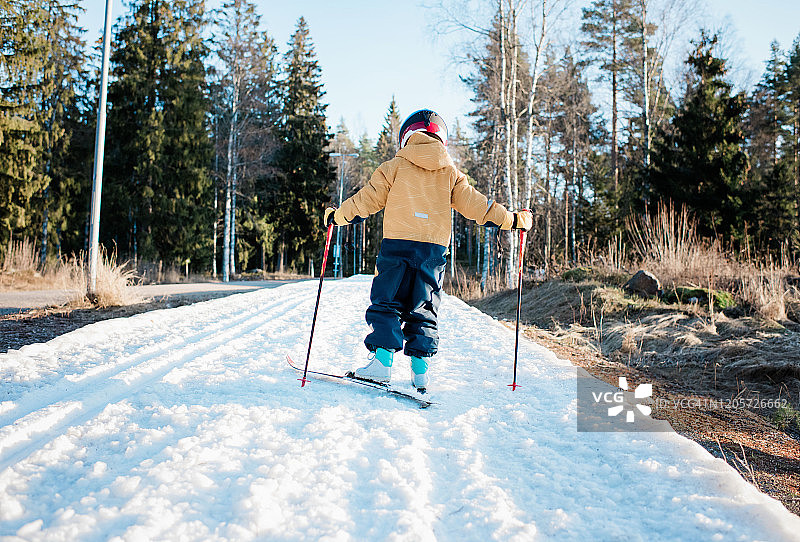 年轻男孩在瑞典日落时越野滑雪背影图片素材